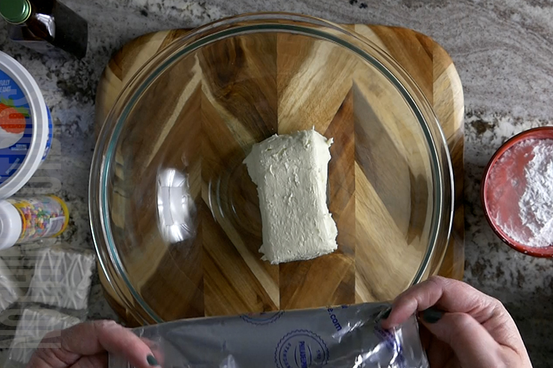 adding softened cream cheese to a mixing bowl to make birthday cake dip