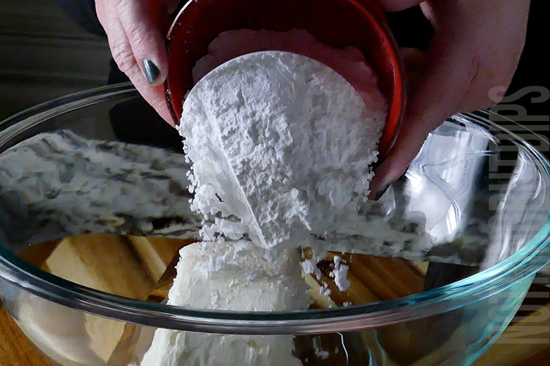 adding powdered sugar to a mixing bowl to make birthday cake dip