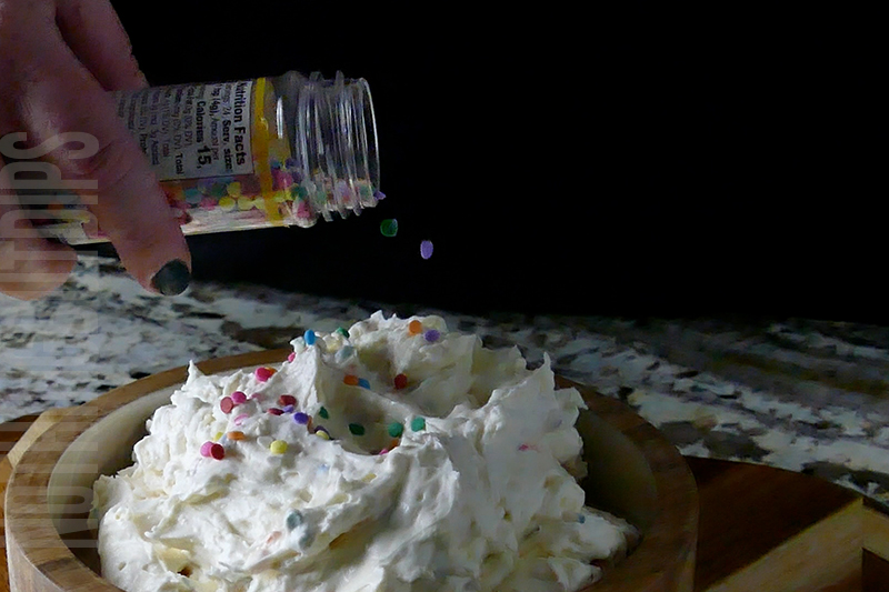 adding some sprinkles to the top of the birthday cake dip
