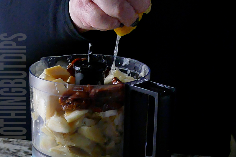 adding a squeeze of lemon to a mini food processor to make baked artichoke dip