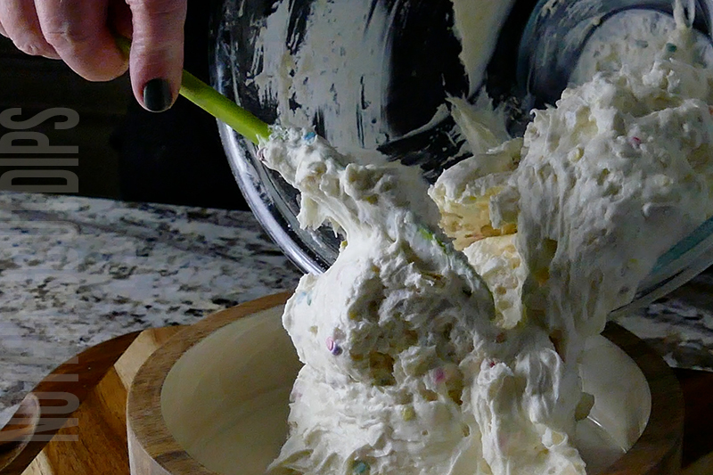 transferring the mixture from the bowl to a serving dish for birthday cake dip