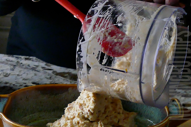 transferring the mix for baked artichoke dip from mini food processor to baking dish 