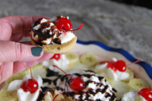 easy banana split dip dessert recipe served on a cookie and topped with a cherry