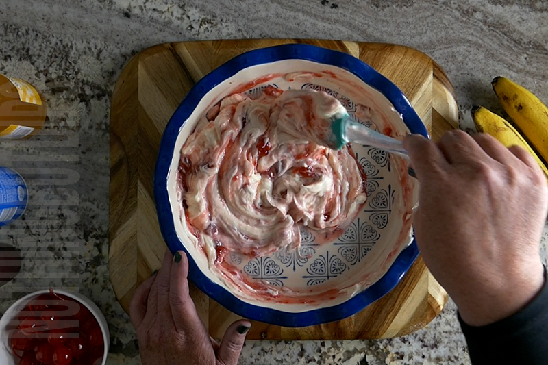 mixing strawberry sundae topping into the creamy base for the banana split dip