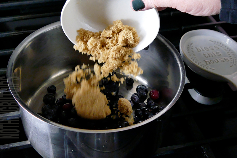 adding brown sugar to a sauce pan to make blueberry compote