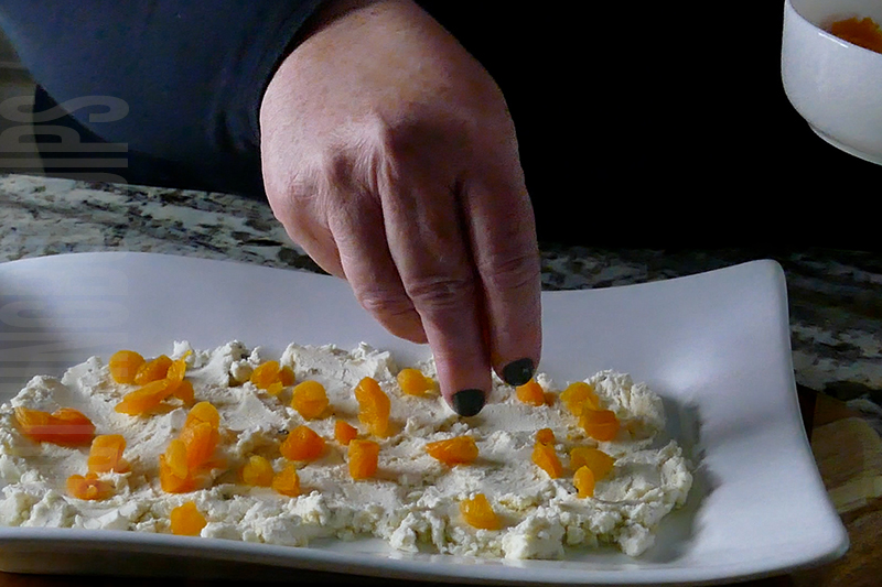adding pieces of dried apricot to the top of Boursin cheese