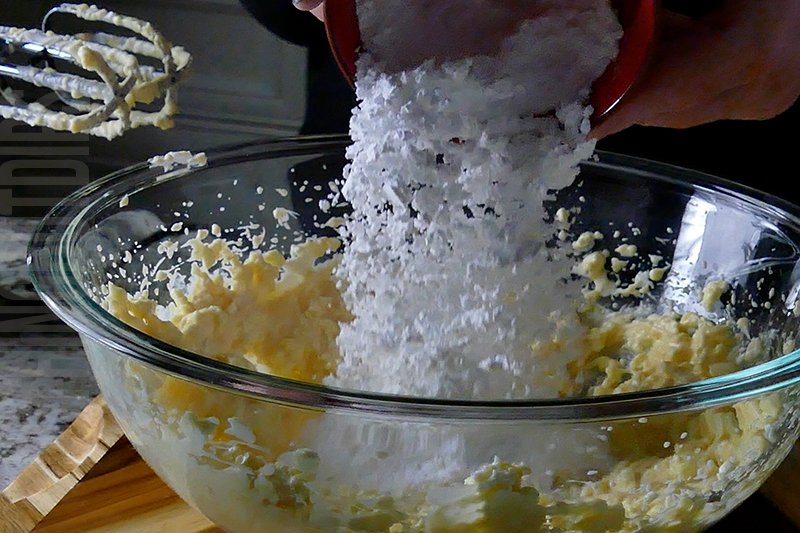 adding powered sugar to the bowl for tropical fruit dip dessert