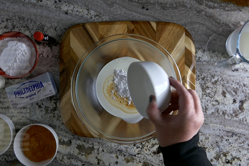 adding ingredients to a bowl to make homemade whipped cream