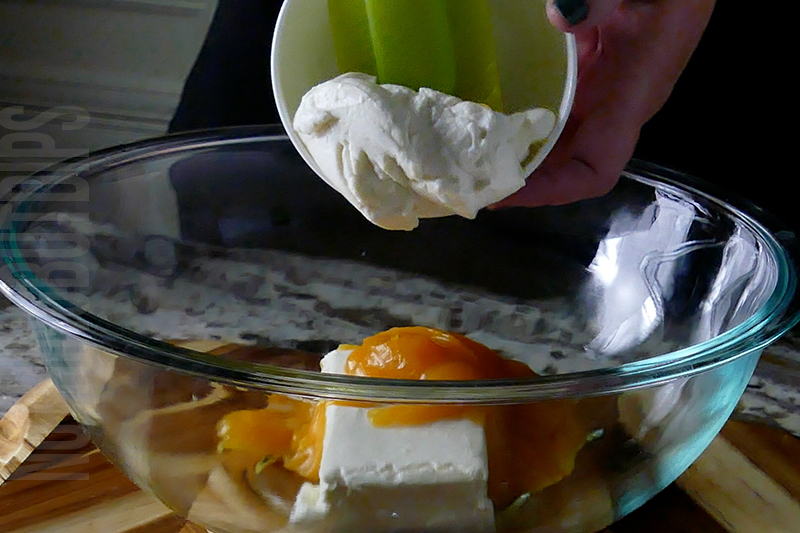 adding ricotta to the bowl for tropical fruit dip dessert