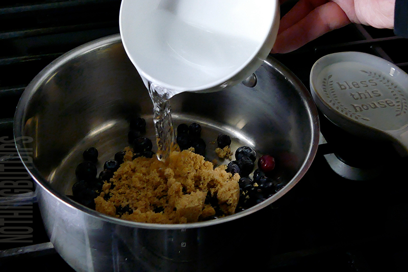 adding water to a sauce pan to make blueberry compote