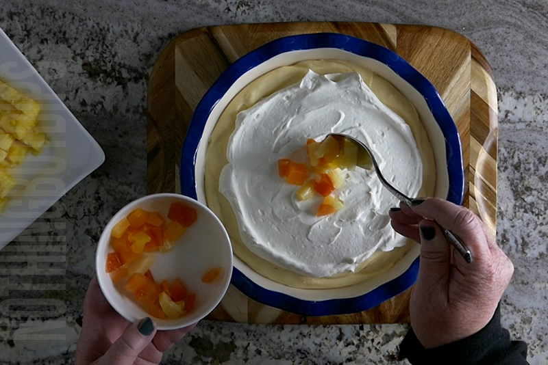 garnishing the tropical fruit dip dessert with diced tropical fruit