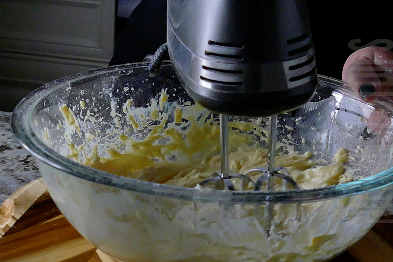 mixing together ingredients with a hand mixer to make the creamy base for tropical fruit dip dessert