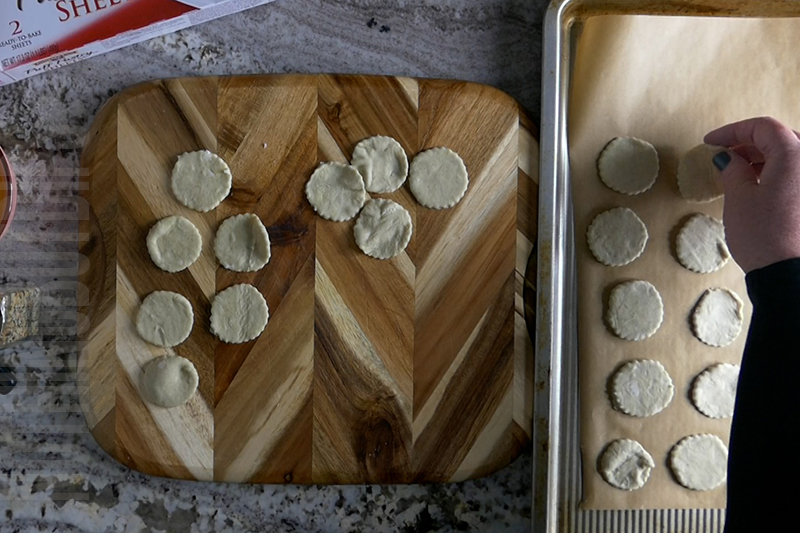 moving the round puff pastry pieces to the lined cookie sheet