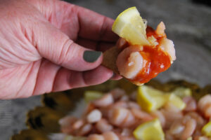 Easy 5-minute shrimp cocktail dip with a lemon garnish and served on a cracker