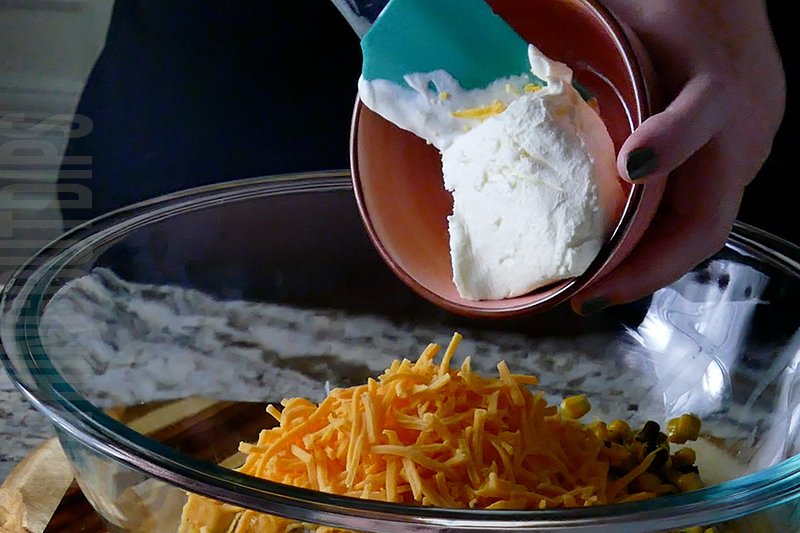 adding cream cheese to the bowl when making Mexican street corn dip