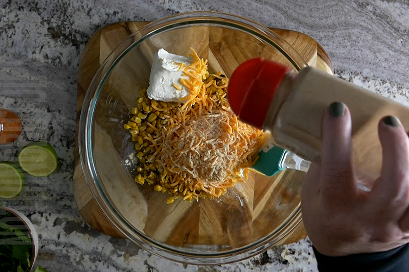 adding onion powder to the bowl when making Mexican street corn dip