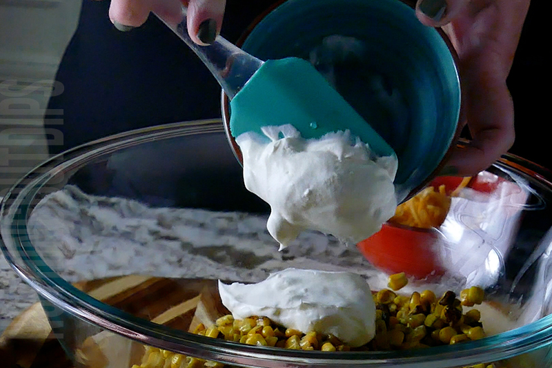 adding sour cream to the bowl when making Mexican street corn dip