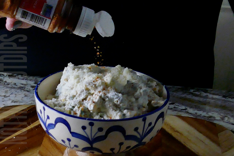 topping the Mexican street corn dip with Tajin seasoning