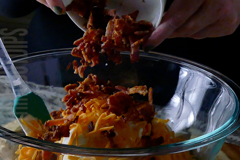 adding bacon pieces to the jalapeno popper cheese ball base