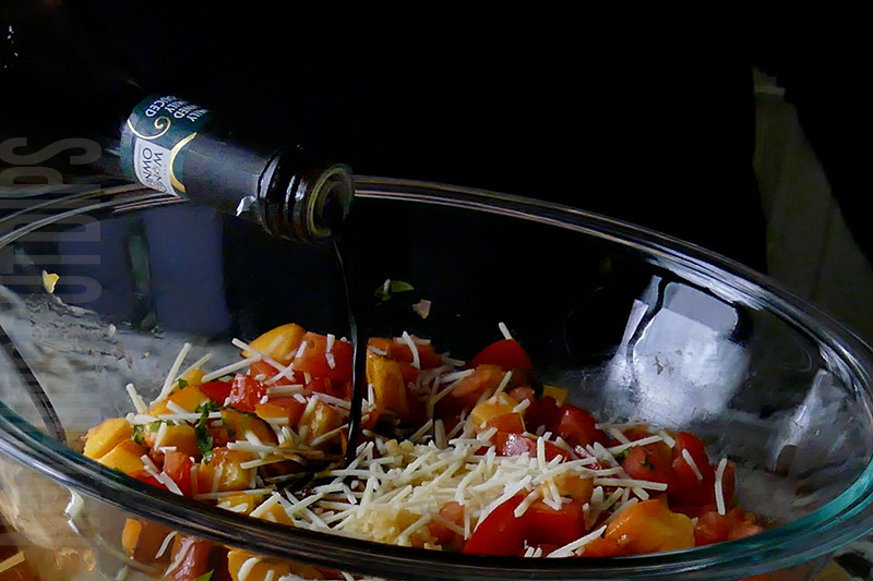 adding balsamic vinegar to the peach and tomato bruschetta