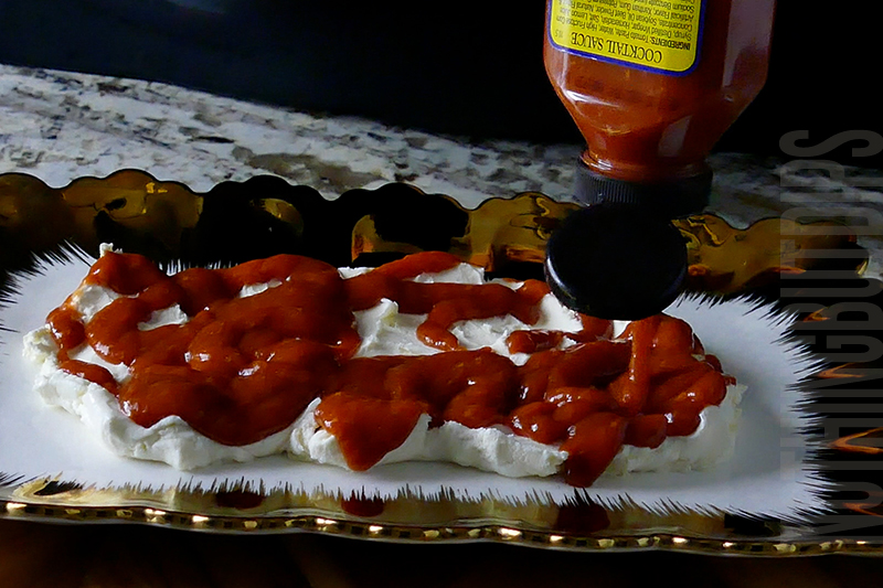 adding cocktail sauce on top of cream cheese