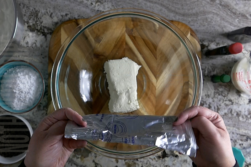 adding cream cheese to the bowl to make mint chocolate chip dip