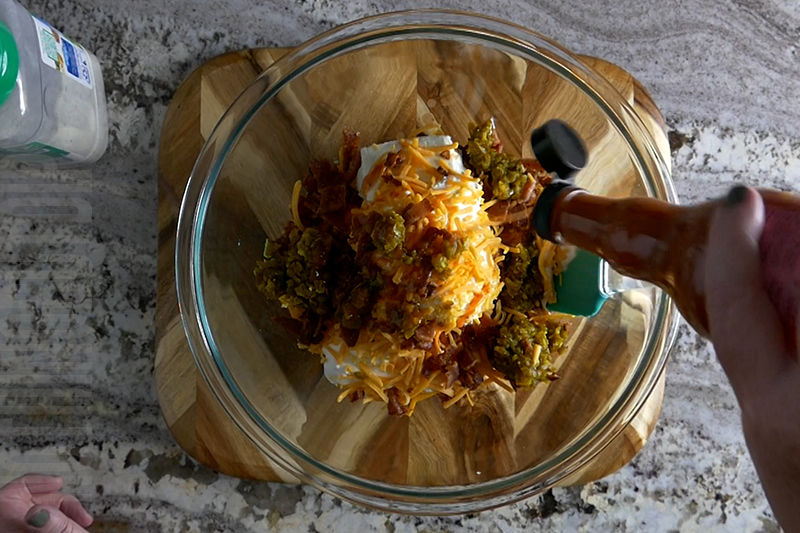 adding hot sauce to the jalapeno popper cheese ball base