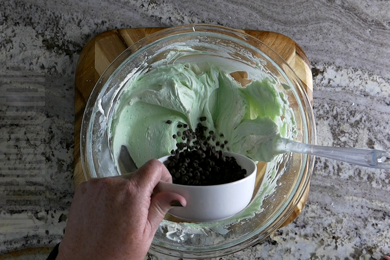 adding mini chocolate chips to the bowl to make mint chocolate chip dip