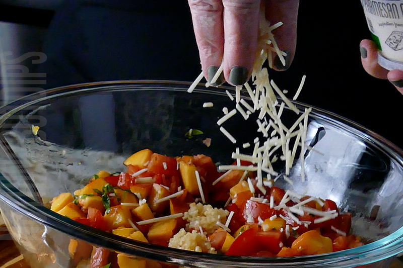 adding grated parmesan to the peach and tomato bruschetta