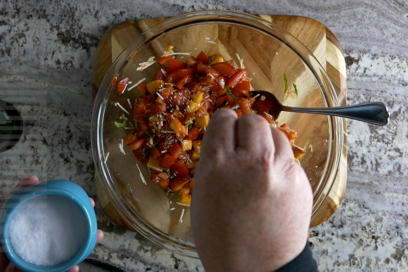 adding salt to the peach and tomato bruschetta
