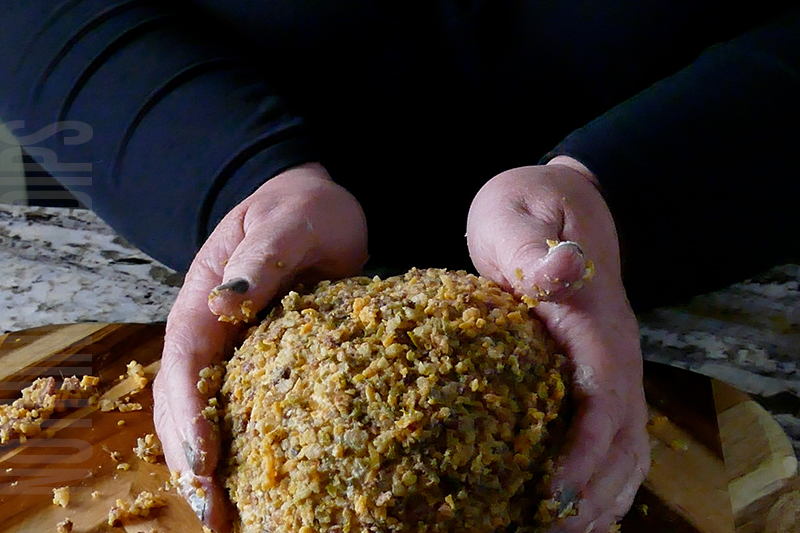 coating the jalapeno popper cheese ball in cheese, nuts, jalapeno peppers and bacon bits