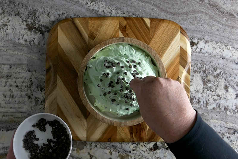 garnishing the mint chocolate chip dip with mini chocolate chips