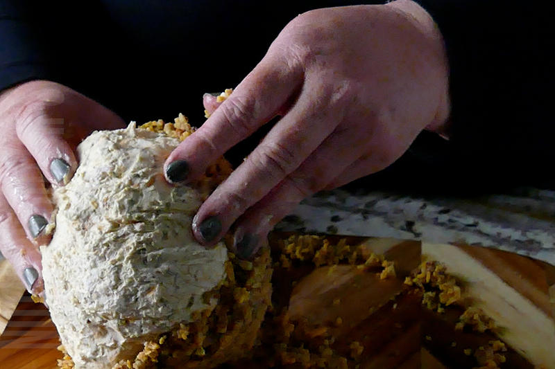 coating the jalapeno popper cheese ball in cheese, nuts, jalapeno peppers and bacon bits