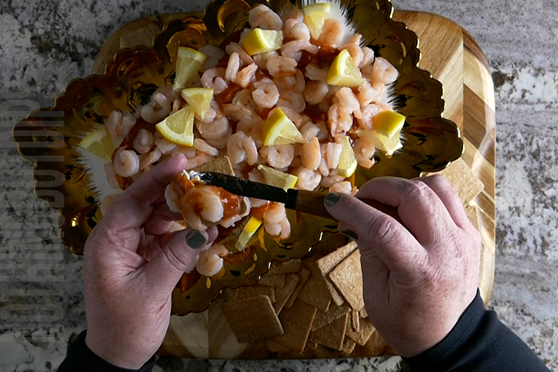 Easy 5-minute shrimp cocktail dip with a lemon garnish and served on a cracker