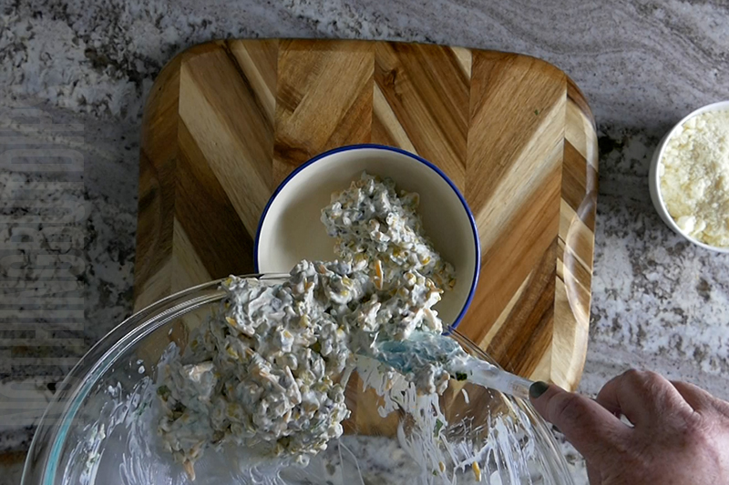transferring the Mexican street corn dip into a serving dish