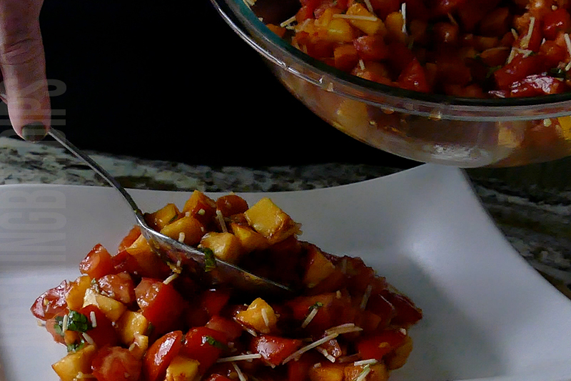transferring the fresh peach and tomato bruschetta from a bowl to a serving platter