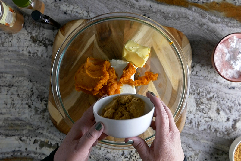 adding brown sugar to the ingredients to make pumpkin cheesecake dip