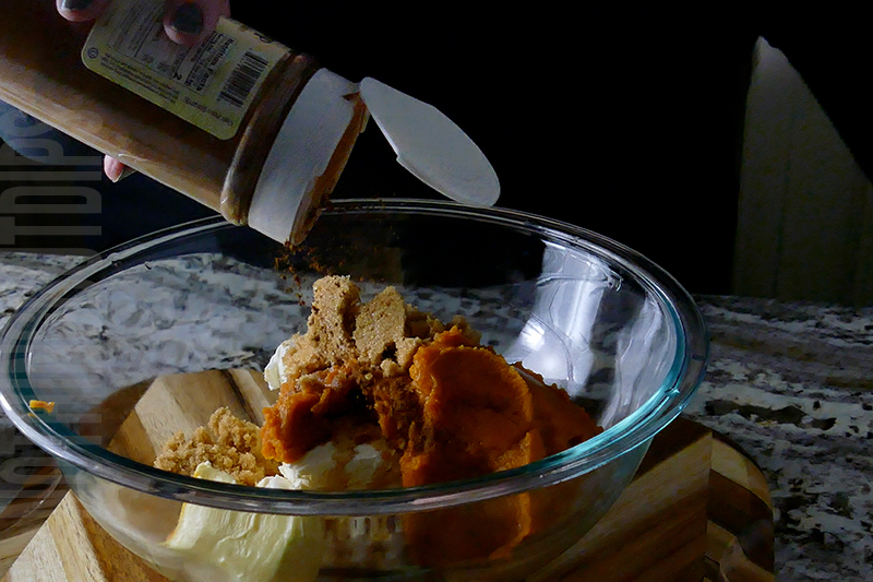 adding pumpkin pie spice to the ingredients to make pumpkin cheesecake dip