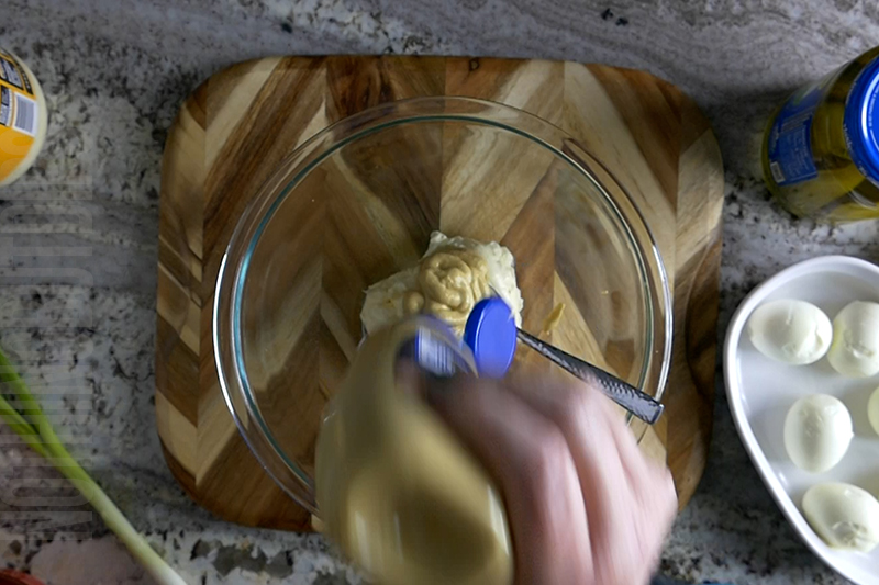 adding dijon mustard to the bowl