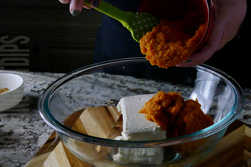 adding pumpkin puree to the ingredients to make pumpkin cheesecake dip