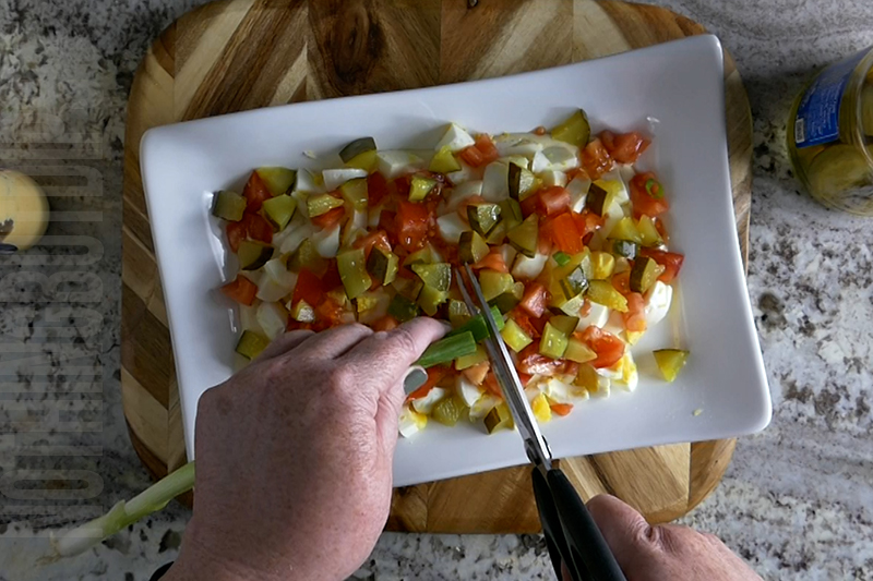 adding chopped green onion to the deviled egg dip