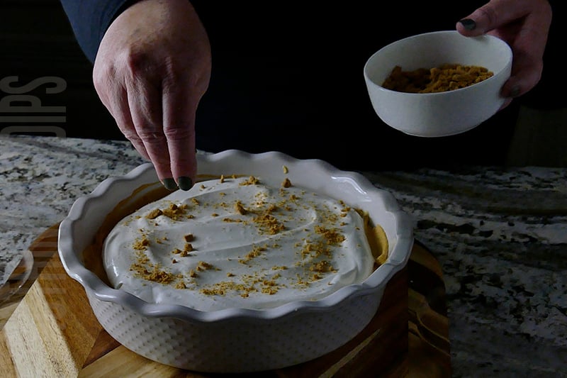 garnishing pumpkin cheesecake dip with crushed gingersnap cookies