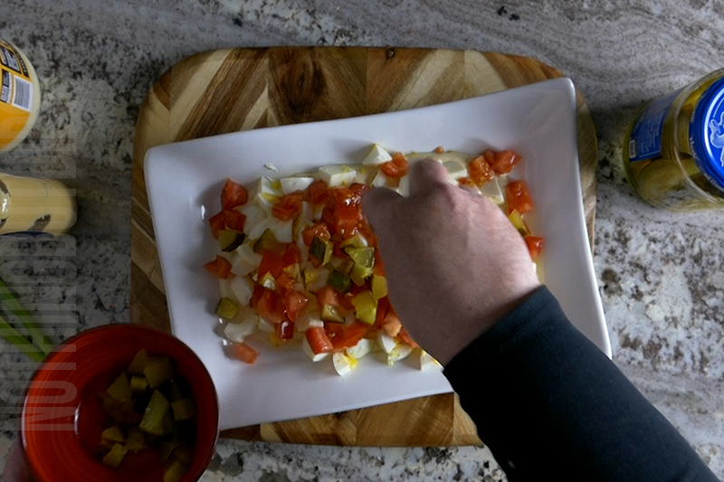 adding dill pickles to the deviled egg dip