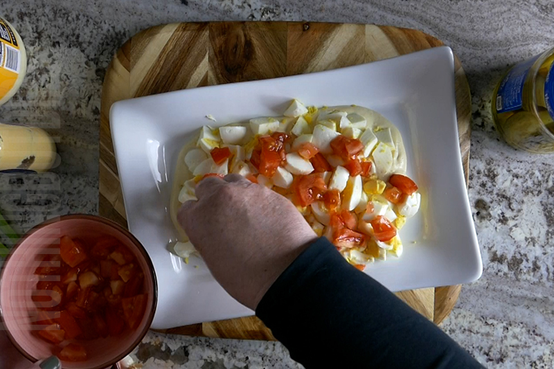 adding tomatoes to the deviled egg dip