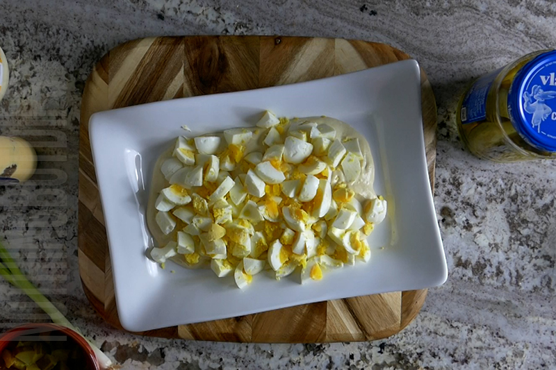 adding boiled eggs to the deviled egg dip